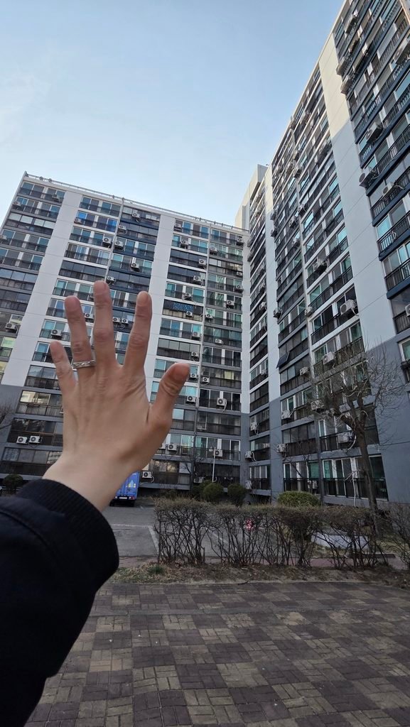 Hand pointing to Korean apartment complex