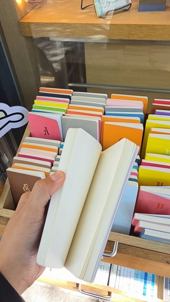 Hand flipping through a blank diary at a Euljiro diary shop